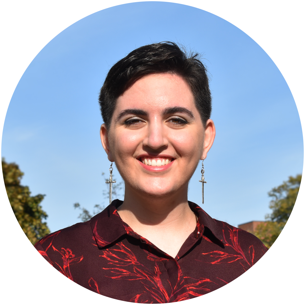 Alyssa Benson's headshot photo. They're wearing a maroon button-up and smiling.